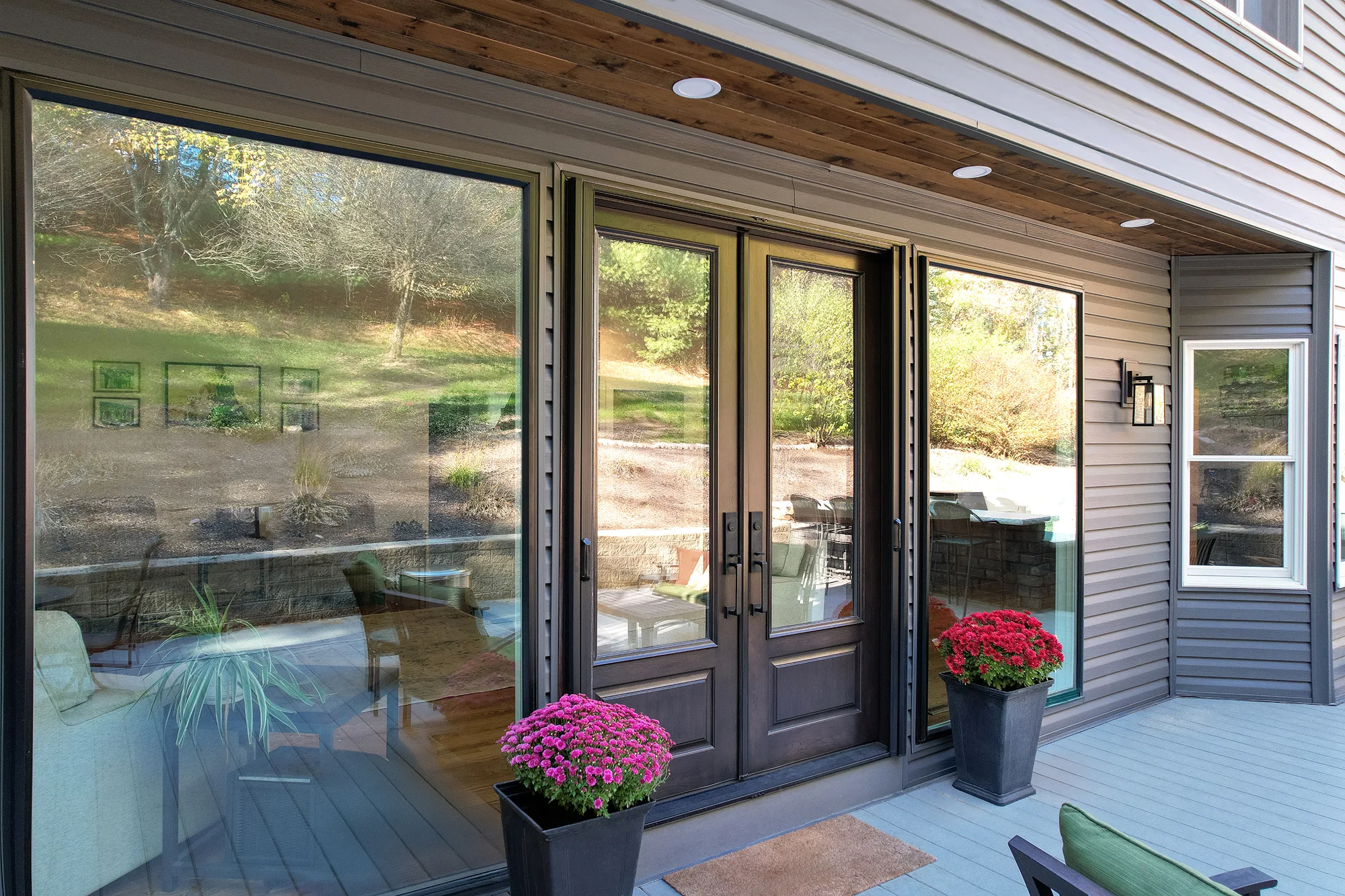 Double glass doors with large windows, potted flowers, and outdoor deck area.